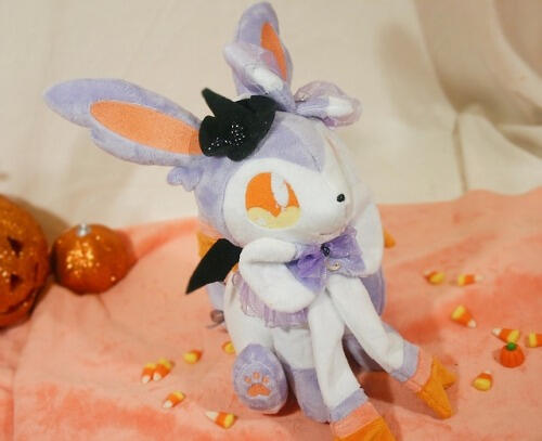 Sylveon plush with a lavender and orange color scheme and tiny witches' and bat wings