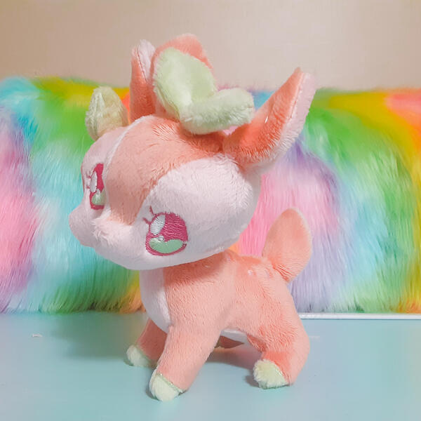 A peach pink two-headed deer plush with green leaf accents