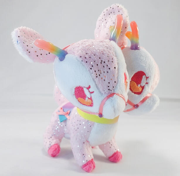 A sparkly pink and white two-headed deer plush with a rainbow harness and horns