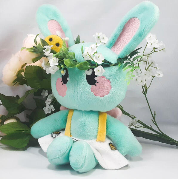 A mint green rabbit plush with a flower crown